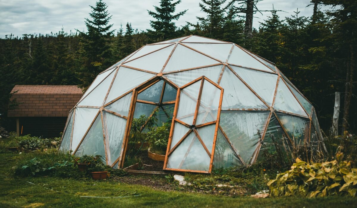A geodesic dome greenhouse stands amidst a vibrant garden with lush greenery. — Photo by Jonathan Cooper on Pexels