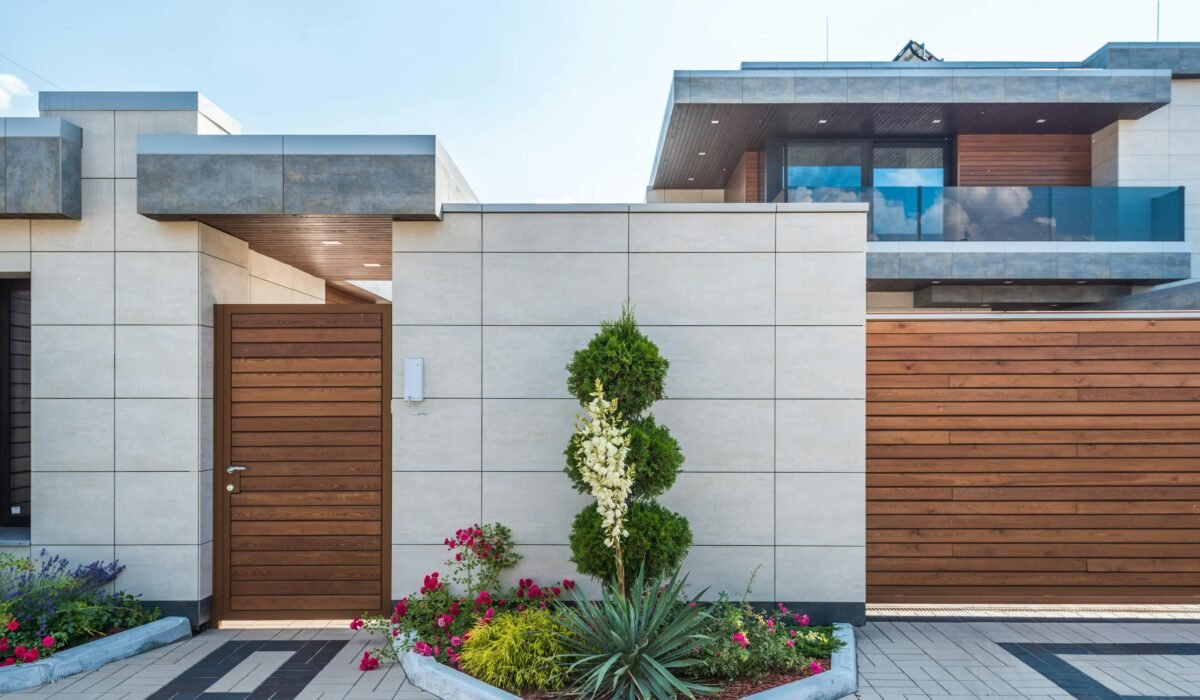 Contemporary house exterior featuring a stylish wooden facade, entrance gate, and vibrant garden. — Photo by Max Vakhtbovych on Pexels