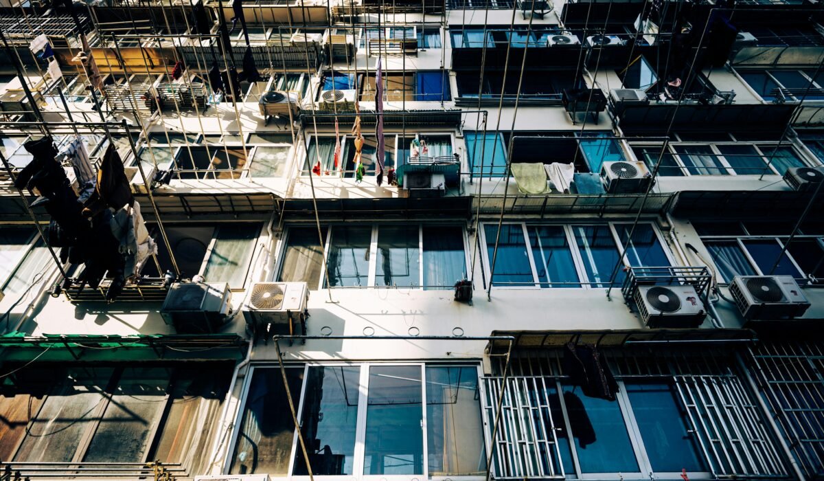 A detailed view of an urban apartment building with windows, balconies, and air conditioning units. — Photo by Zhengyang TIAN on Pexels