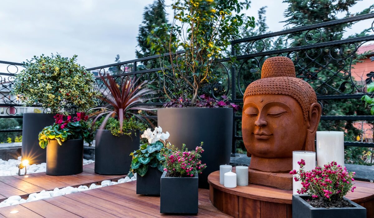 A tranquil Buddha statue in a modern garden with lush plants and candles, creating a zen atmosphere. — Photo by Nasim Didar on Pexels