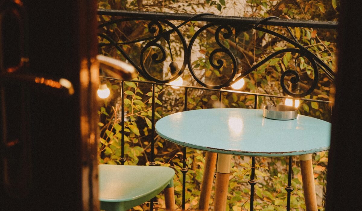 Charming balcony setup with a blue table, chair, and warm lights, inviting a serene evening vibe. — Photo by Rahib Yaqubov on Pexels