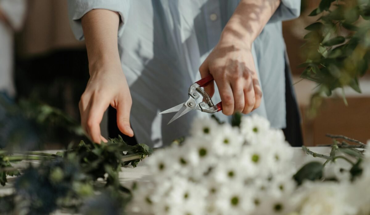 Florist arranging a floral bouquet with scissors on a sunny day. — Photo by cottonbro studio on Pexels