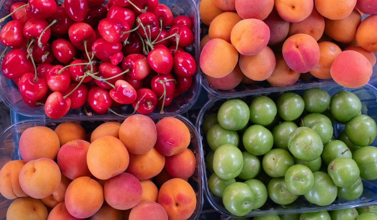 Top view of fresh cherries, apricots, and plums displayed in trays, showcasing vibrant colors. — Photo by Doğan Alpaslan Demir on Pexels