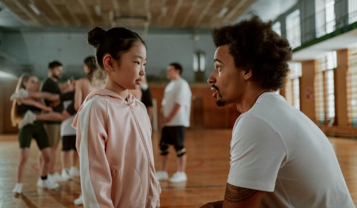 Coach and young girl engage in focused conversation during gym training session. — Photo by cottonbro studio on Pexels