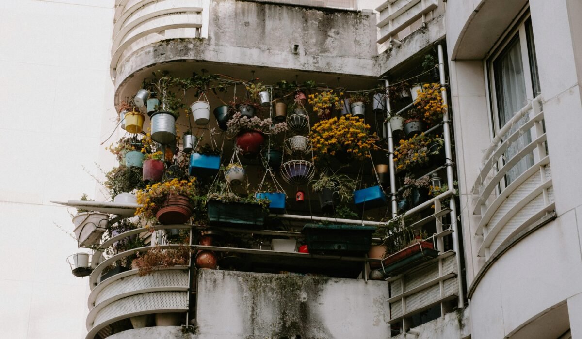 Low angle view of a balcony brimming with vibrant potted plants on a building exterior. — Photo by Mathias Reding on Pexels